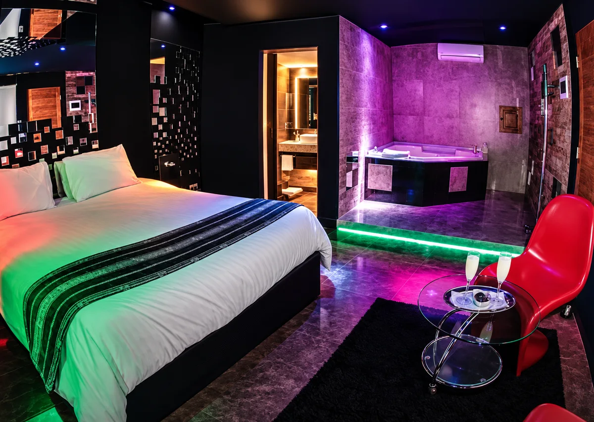 Habitación de Saint Valentine con luces verdes y moradas, sillón rojo y jacuzzi